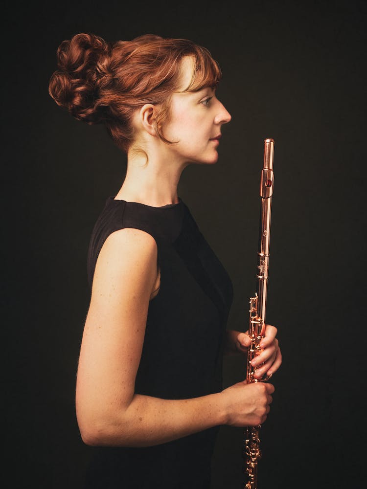 Fiona in a black dress, looking to the side and holding her flute.