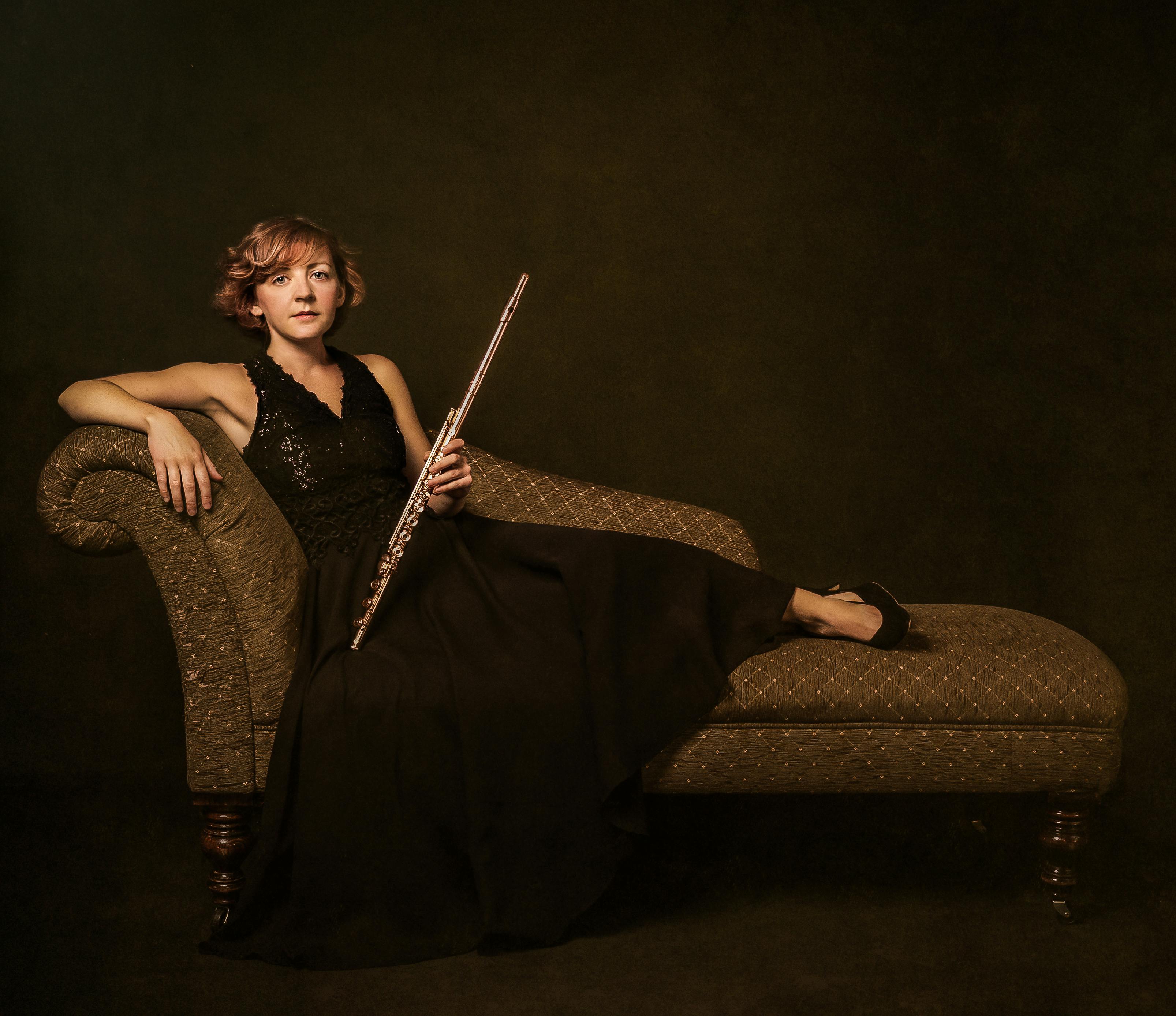 Portrait of Fiona lounging on a couch with her flute.